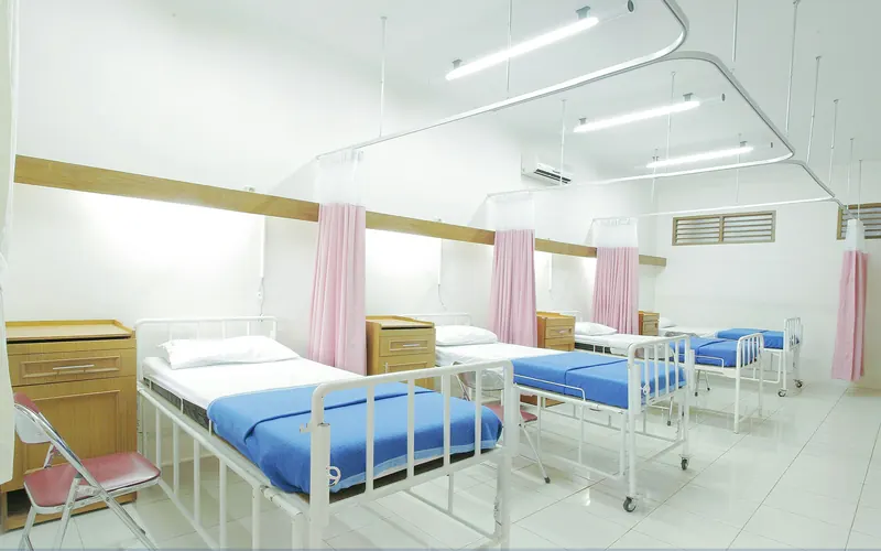 Empty hospital ward bay with made-up beds and privacy curtains